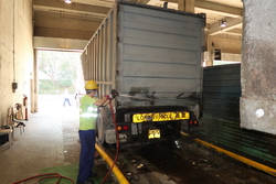 Image of The operator in the compactor hall at lower floor closes the container door and washes the container before leaving.